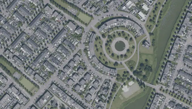 Luchtfoto van een woonwijk met ronde en rechte straten en groene gebieden.